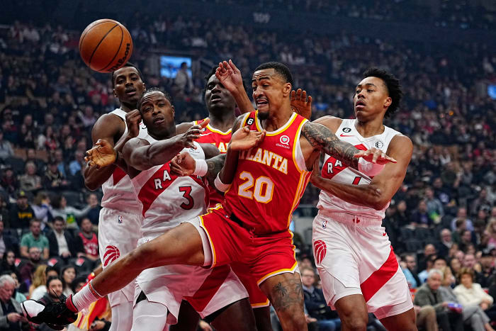 Hawks forward John Collins battles for the ball against Raptors defenders.
